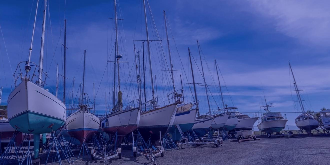 Sailboats and power cruisers up on stands and cradles in the gravel yard at East Boothbay, masts bare against the sky.