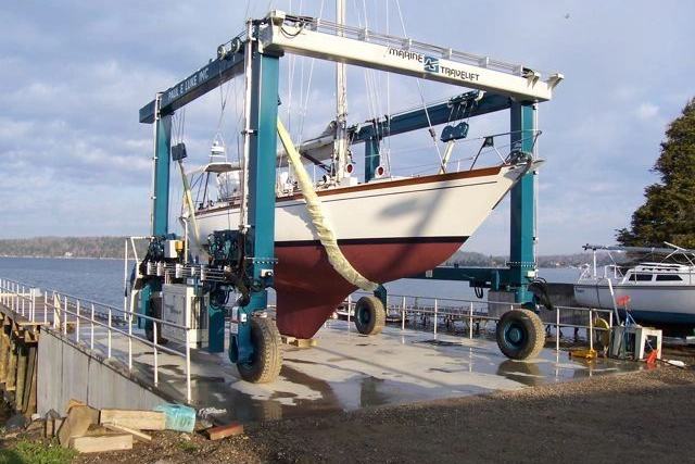 A sailboat in the slings of the yard's 35 ton travel lift on the waterfront.
