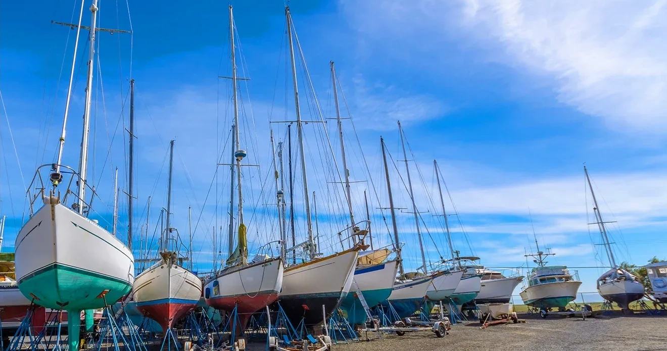 Sailboats and powerboats blocked up on stands in the yard for the winter.